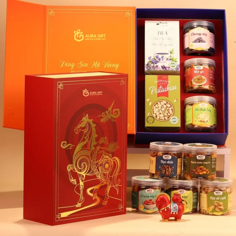 Hộp quà Tết đỏ ép kim ngựa đặt cạnh hộp mở chứa trà, hạt dẻ cười và các hũ đồ khô
