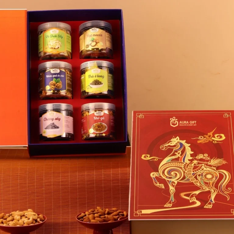 Hộp quà Tết mở với 6 hũ hạt và đồ khô xếp khay đỏ, bên cạnh nắp đỏ ép kim ngựa